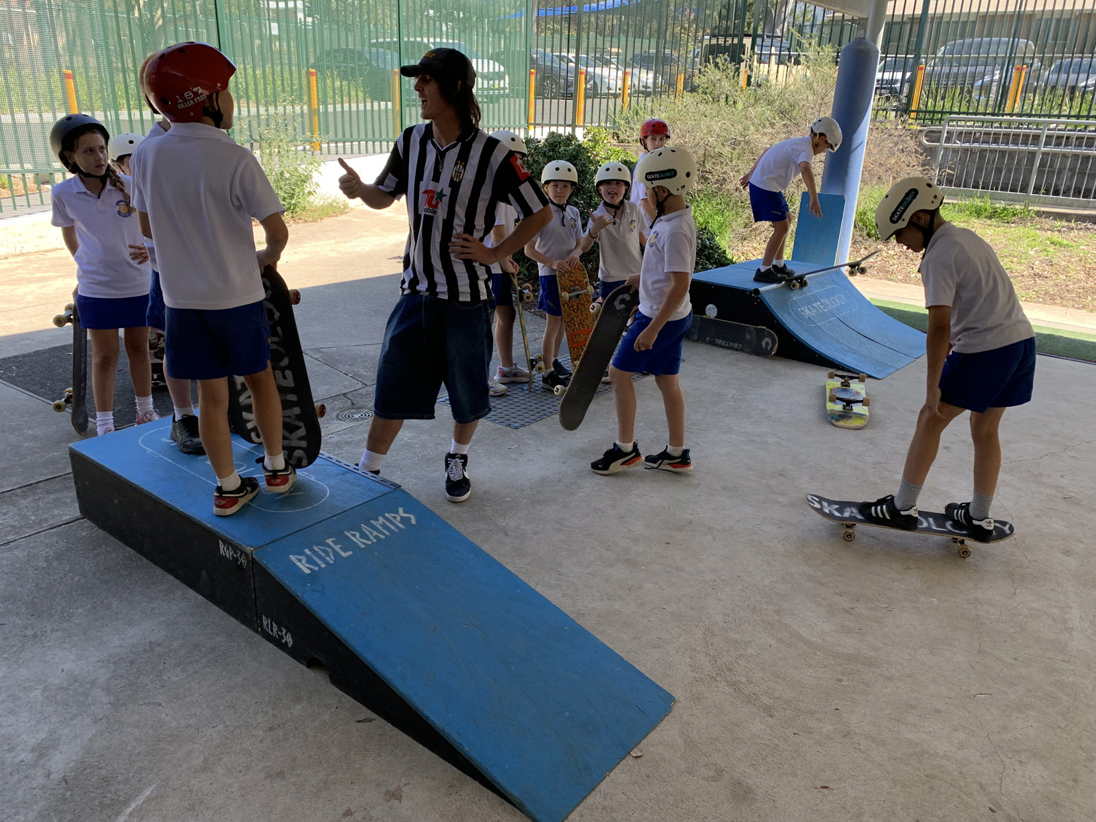 Kids at school learning to skateboard.
